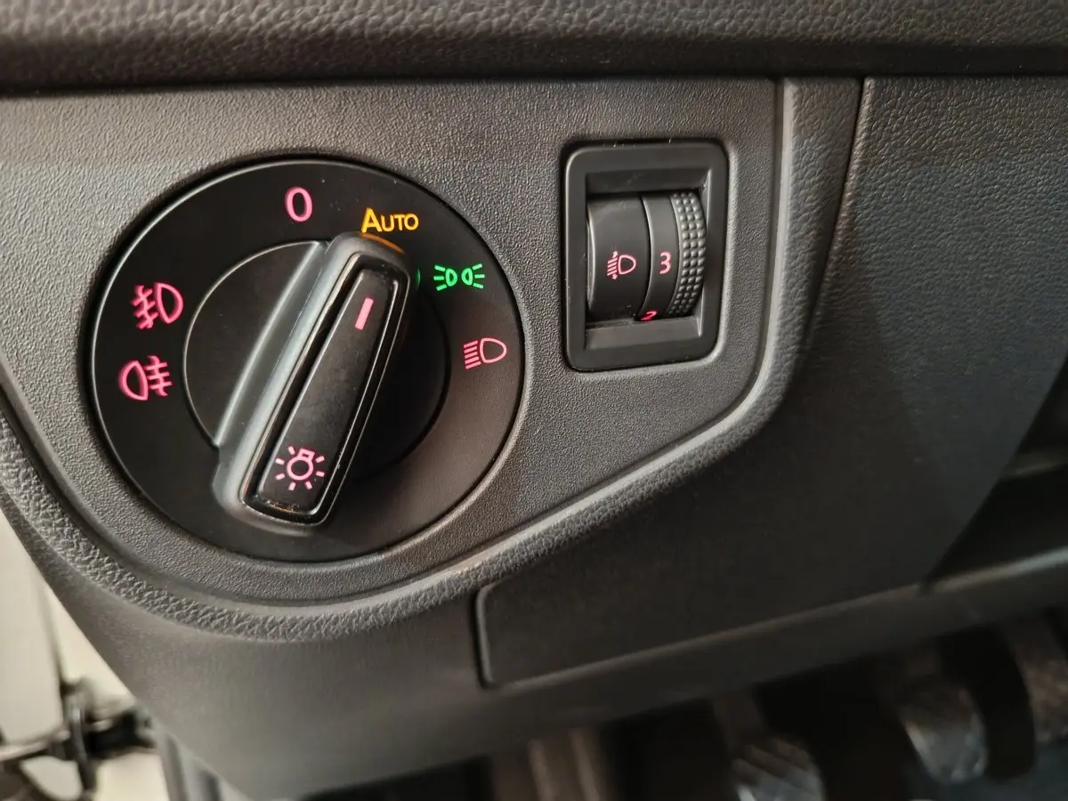 Gros plan sur le bouton de commande des phares et réglage hauteur des feux dans une Volkswagen Polo blanche 2020.