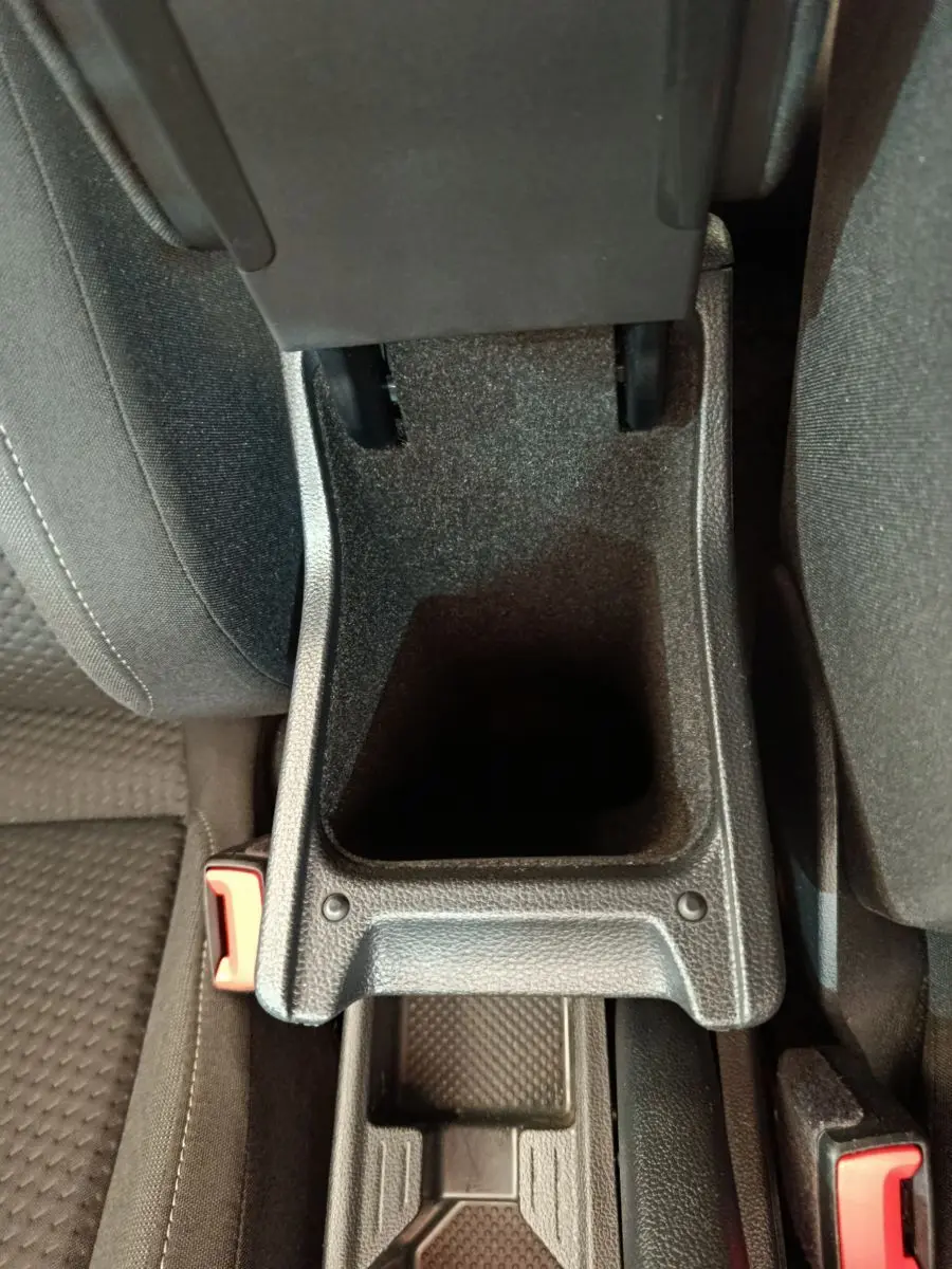 Vue plongeante sur le rangement central noir entre les sièges avant d'une Volkswagen Polo blanche 2020.