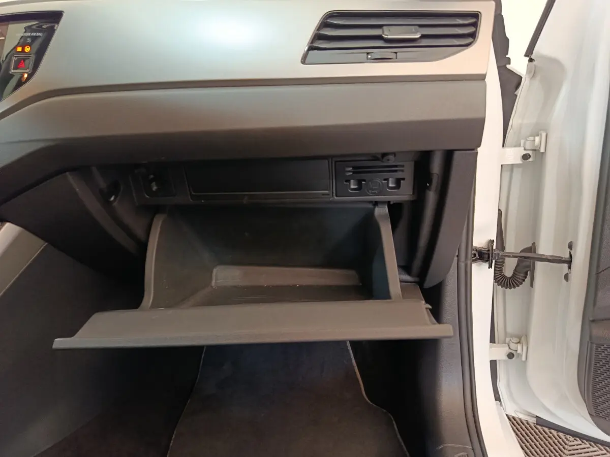 Gros plan sur la boîte à gants ouverte côté passager d'une Volkswagen Polo blanche, intérieur noir et gris.