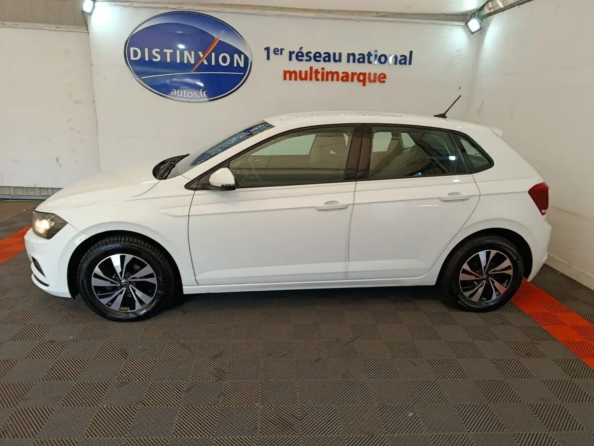 Profil côté gauche d'une Volkswagen Polo blanche 2020 stationnée en intérieur avec jantes alliage bicolores.