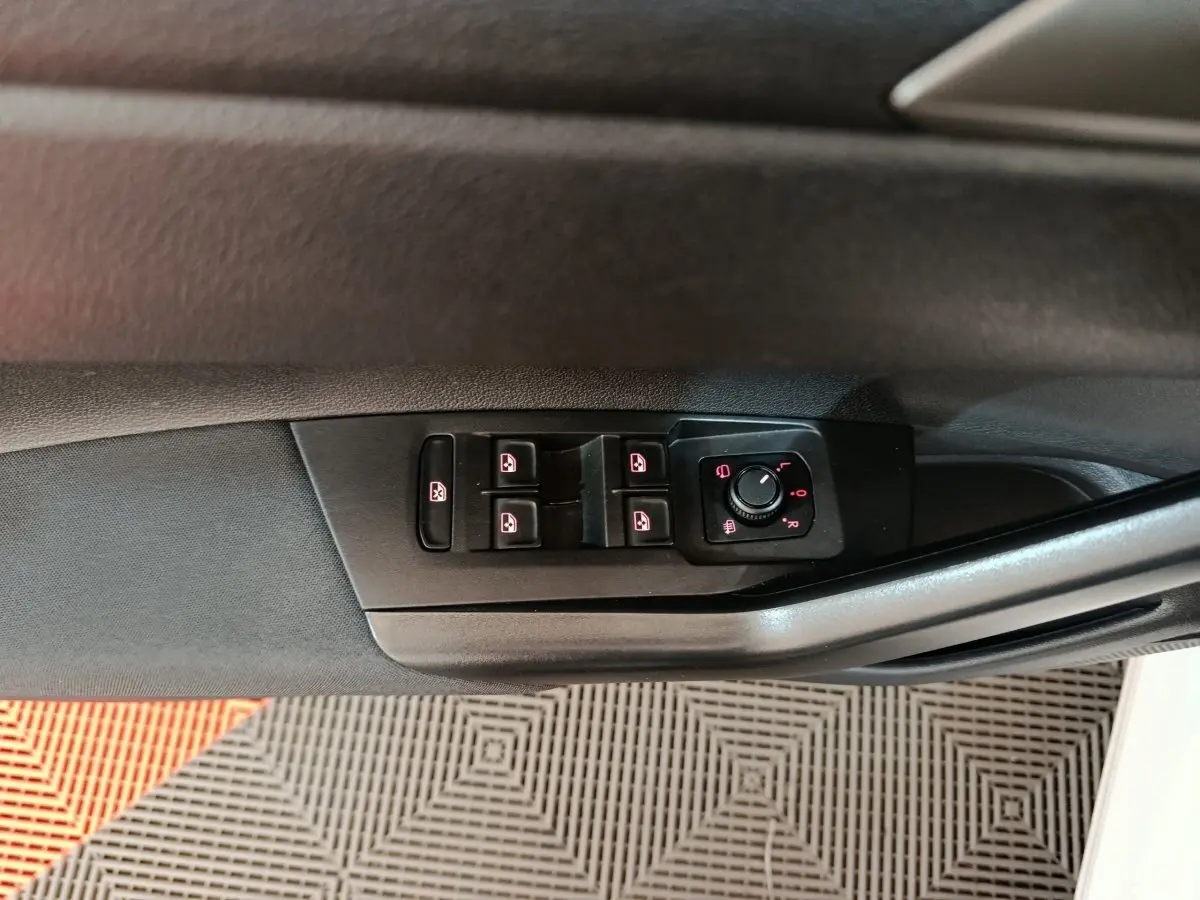 Gros plan sur les commandes de lève-vitres et rétroviseurs côté conducteur d'une Volkswagen Polo blanche 2020.