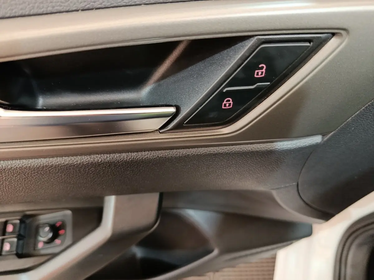Détail de la poignée intérieure et des boutons de verrouillage de porte côté conducteur d'une Volkswagen Polo blanche 2020.