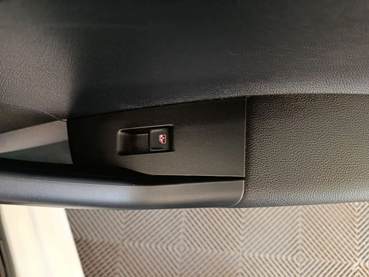 Bouton de verrouillage centralisé sur la porte intérieure noire d'une Volkswagen Polo blanche vue côté gauche.