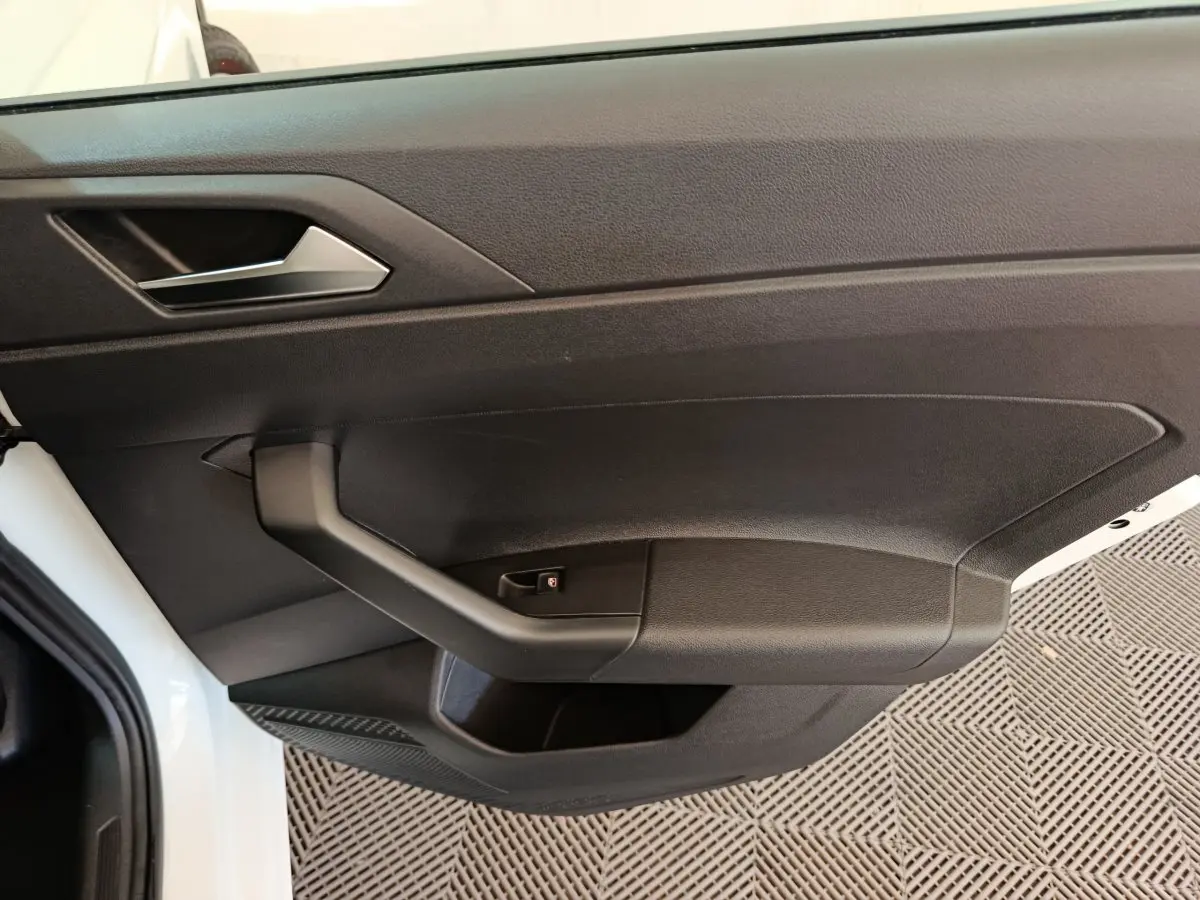 Vue rapprochée de la porte avant gauche noire d'une Volkswagen Polo blanche 2020, avec poignée intégrée.