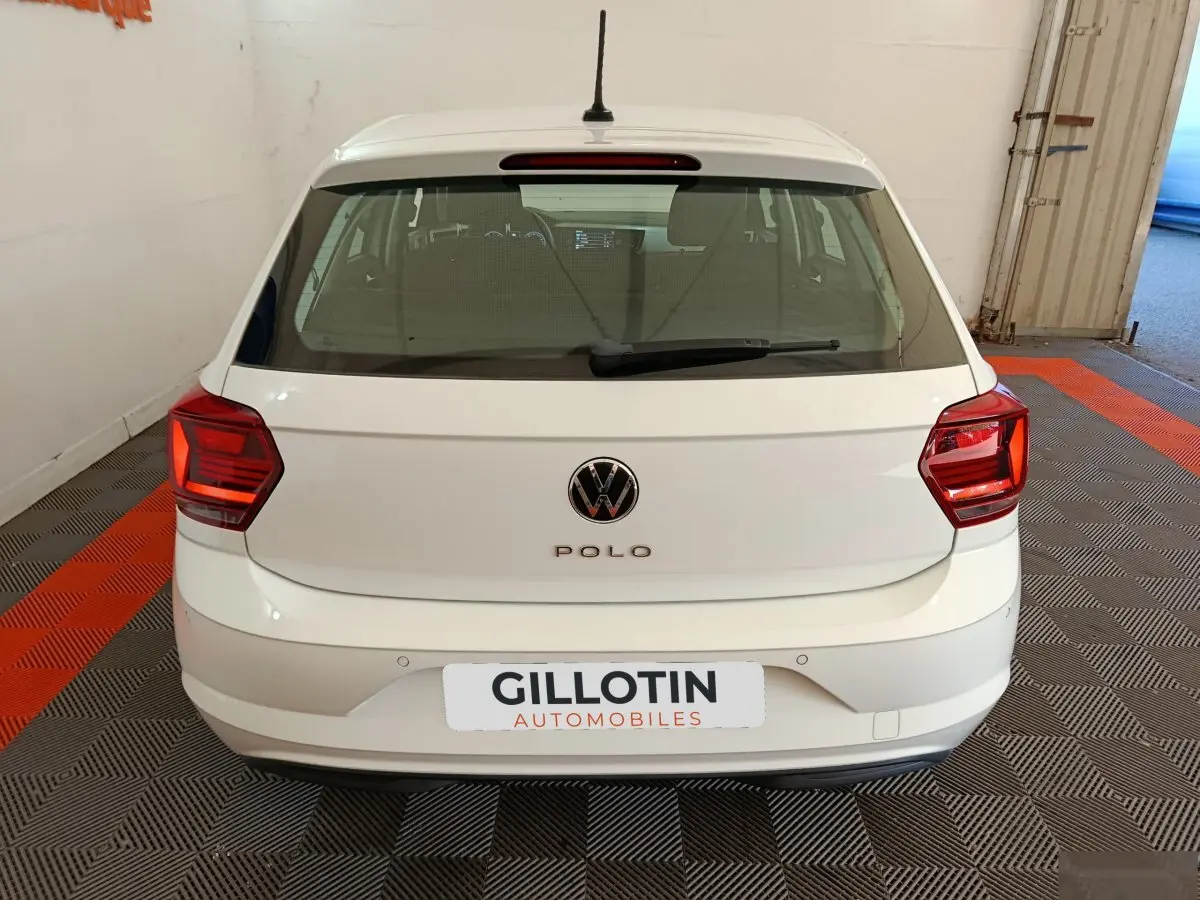 Vue arrière d'une Volkswagen Polo blanche 2020 stationnée en intérieur avec logo VW visible et feux rouges.