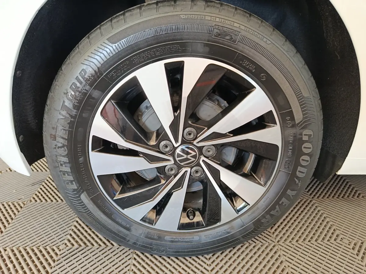 Gros plan sur la roue avant droite d'une Volkswagen Polo blanche, jante alliage bicolore noir et argent.