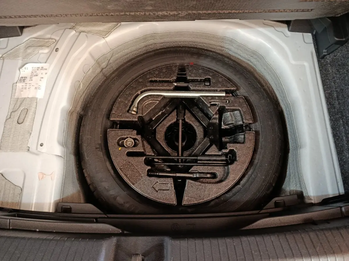 Vue plongeante sur la roue de secours et les outils de bord dans le coffre d'une Volkswagen Polo blanche 2020.