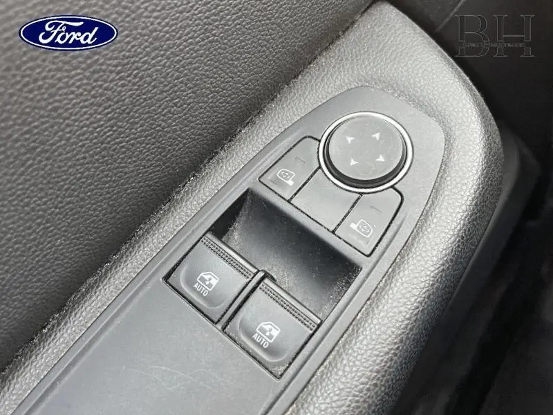 Gros plan sur les commandes de lève-vitres et rétroviseurs noirs dans l'habitacle d'une Renault Clio Gris Platine.