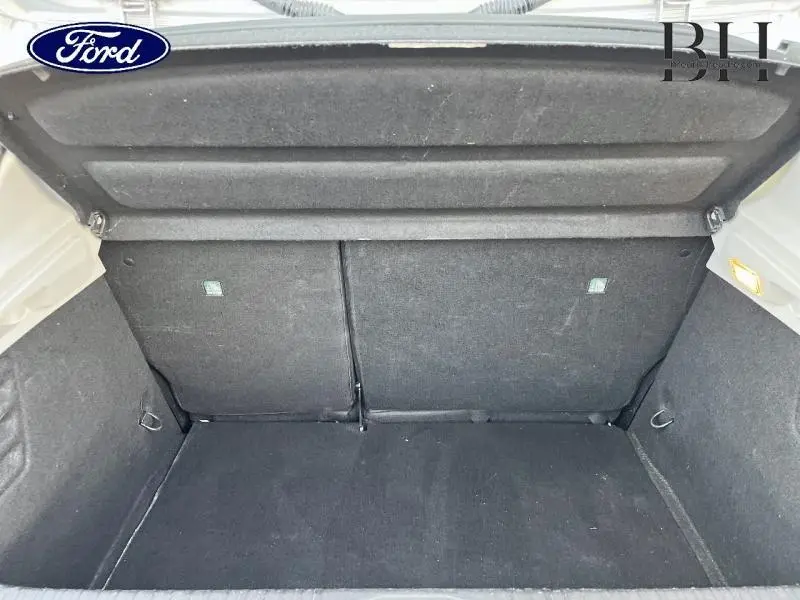 Coffre ouvert vu de face d'une Renault Clio gris platine, montrant l'espace de chargement et la moquette noire.