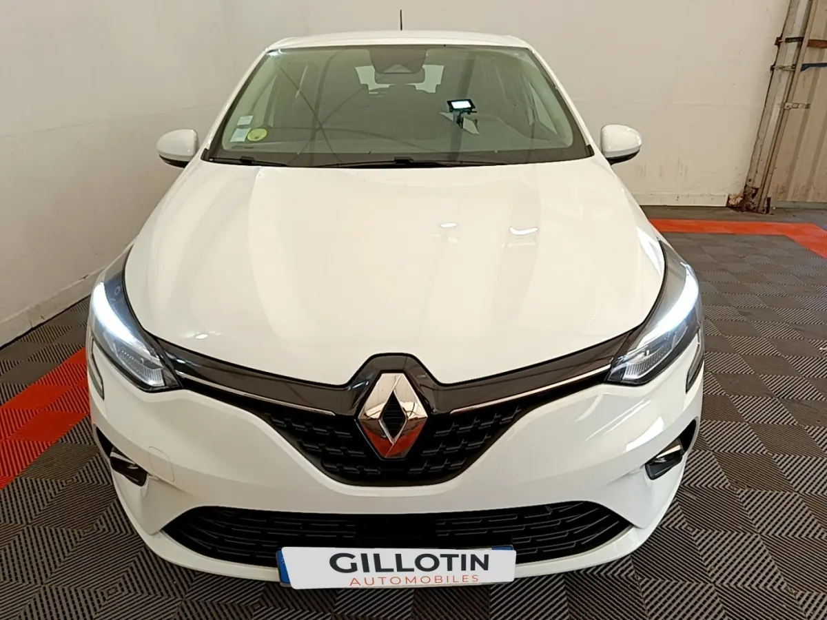 Vue avant d'une Renault Clio Business Blue dCi 85 blanche avec phares LED allumés dans un garage.