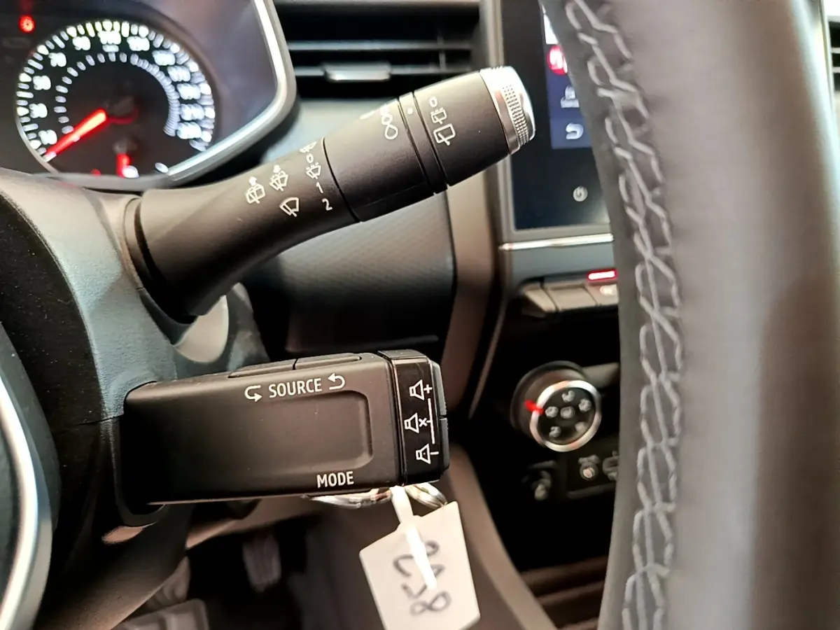 Gros plan sur le volant et commandes au volant de la Renault Clio Business Blue dCi 85, tableau de bord partiellement visible.