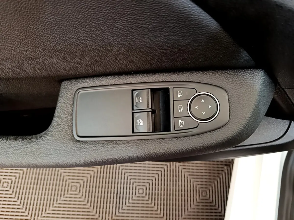 Commande des vitres et rétroviseurs sur la porte côté conducteur d'une Renault Clio Business Blue dCi 85 blanche, vue intérieure rapprochée.