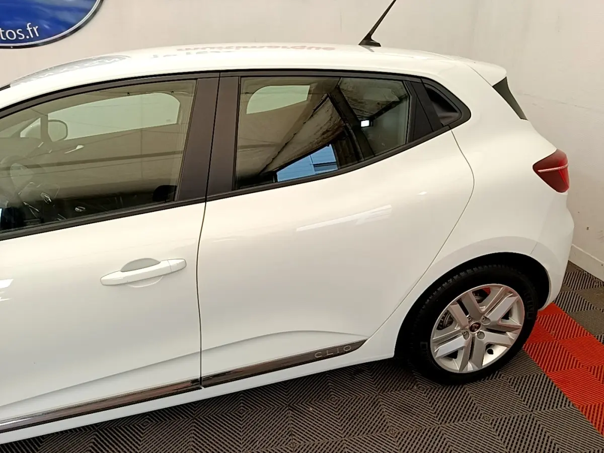 Vue latérale côté droit d'une Renault Clio blanche Business Blue dCi 85 avec jantes alliage et logo Clio sur la bas de caisse.