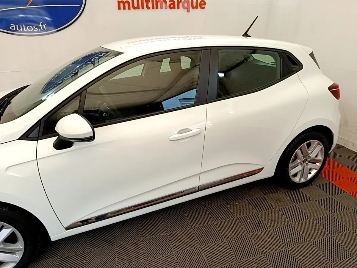 Profil côté gauche d'une Renault Clio Business Blue dCi 85 blanche, avec jantes alliage et rétroviseurs blancs.