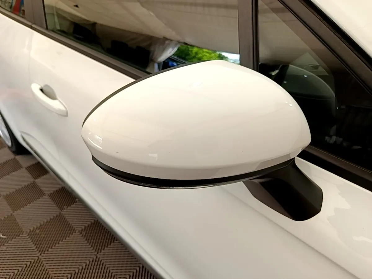 Gros plan sur le rétroviseur droit blanc d’une Renault Clio Business Blue dCi 85 de 2020, avec porte et vitre arrière visibles.