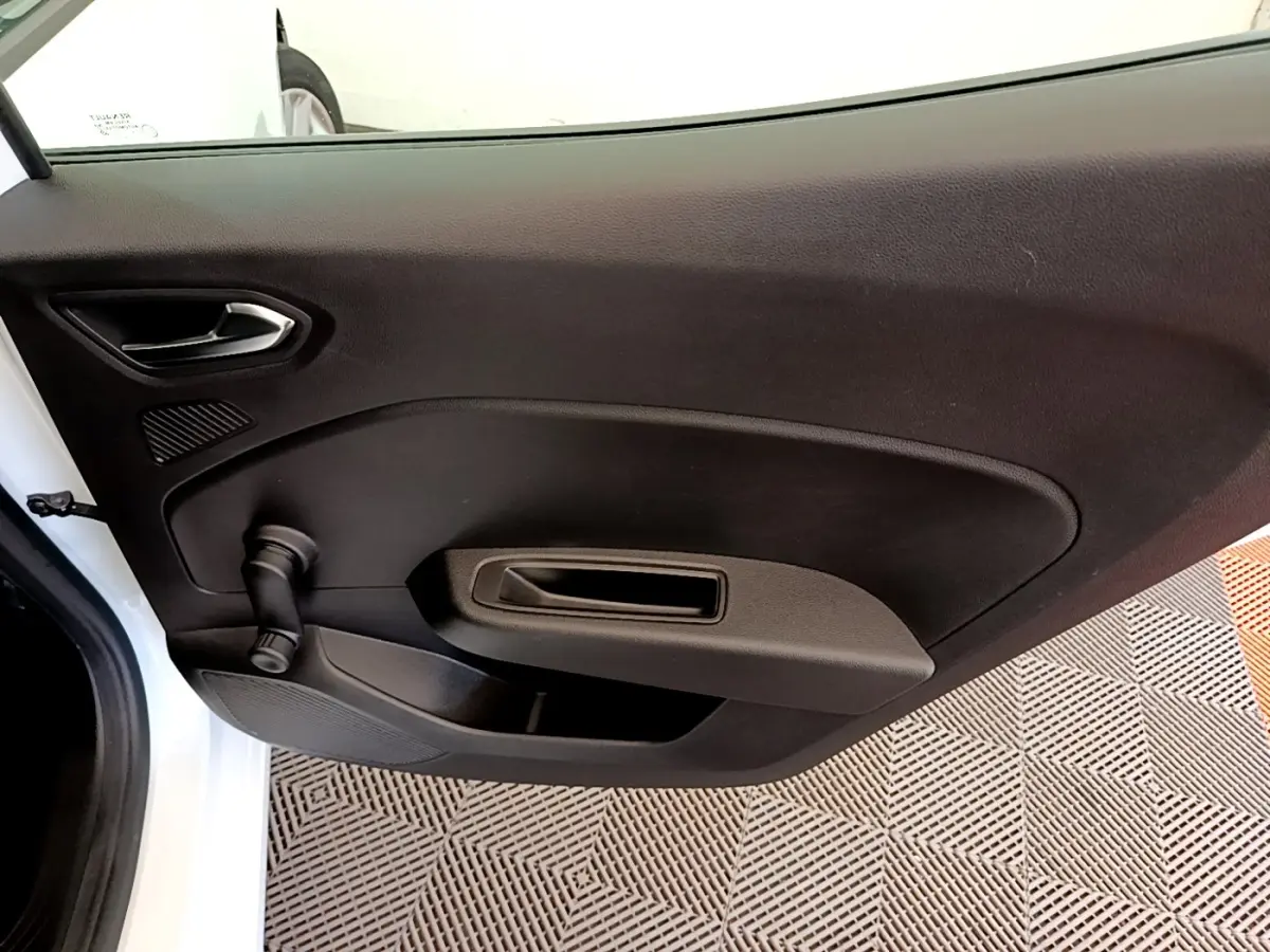 Vue intérieure de la porte arrière gauche noire d'une Renault Clio Business Blue dCi 85 blanche, avec poignée et manivelle de vitre.