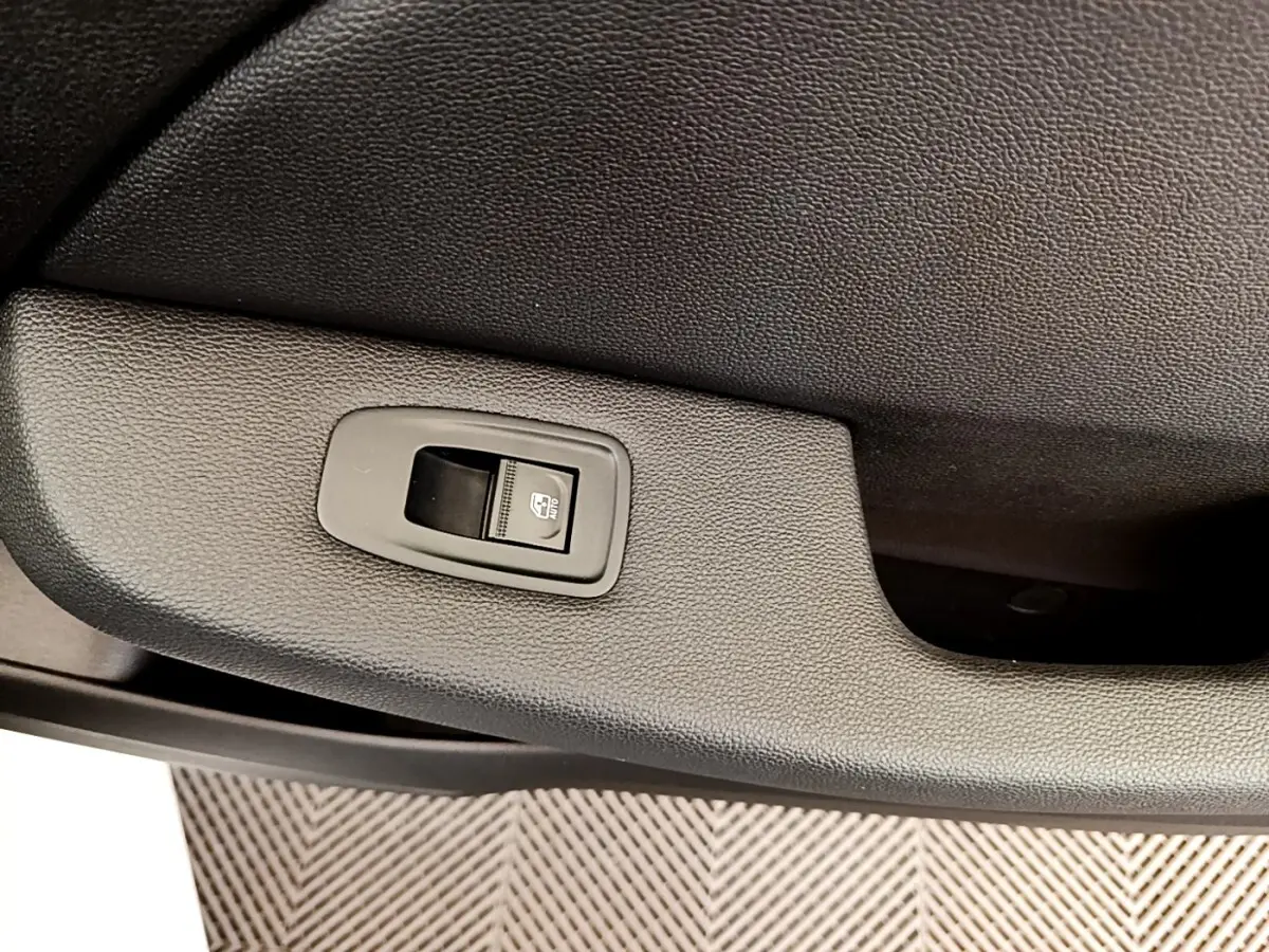 Gros plan sur le bouton de commande de la vitre électrique côté porte intérieure, finition noire texturée.