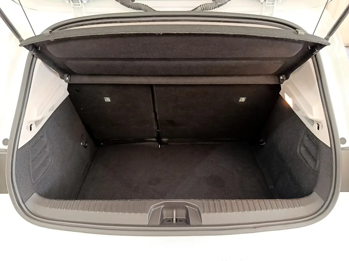 Vue plongeante sur le coffre ouvert d’une Renault Clio Business Blue dCi 85 blanc, montrant l’espace de rangement noir.