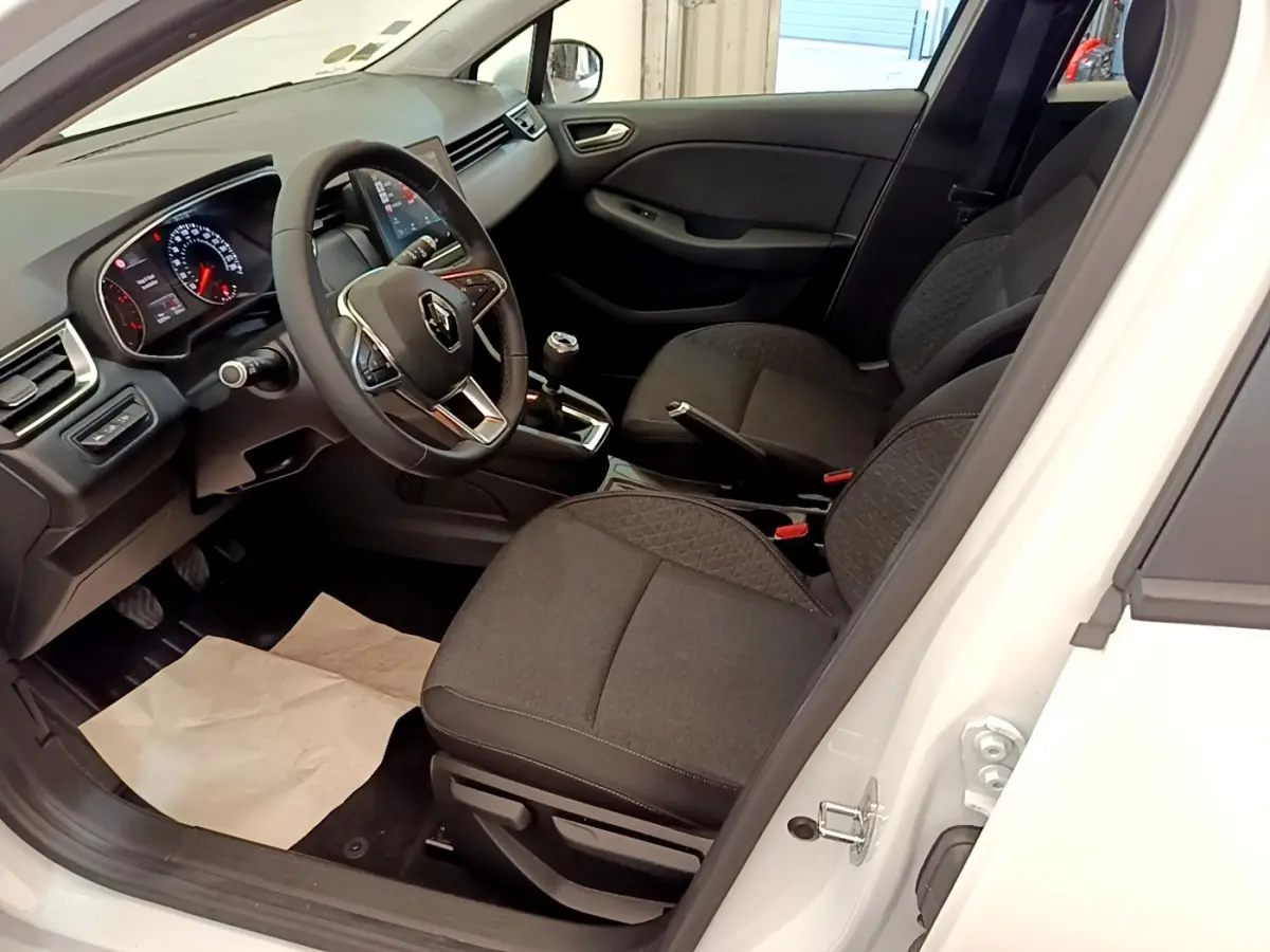 Vue intérieure côté conducteur de la Renault Clio Business Blue dCi blanche, montrant le volant cuir et la console centrale.