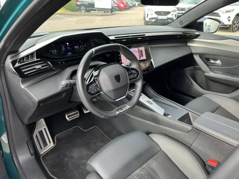 Vue intérieure côté conducteur du Peugeot 308 SW 2023 avec volant multifonction, écran tactile et sellerie noire.