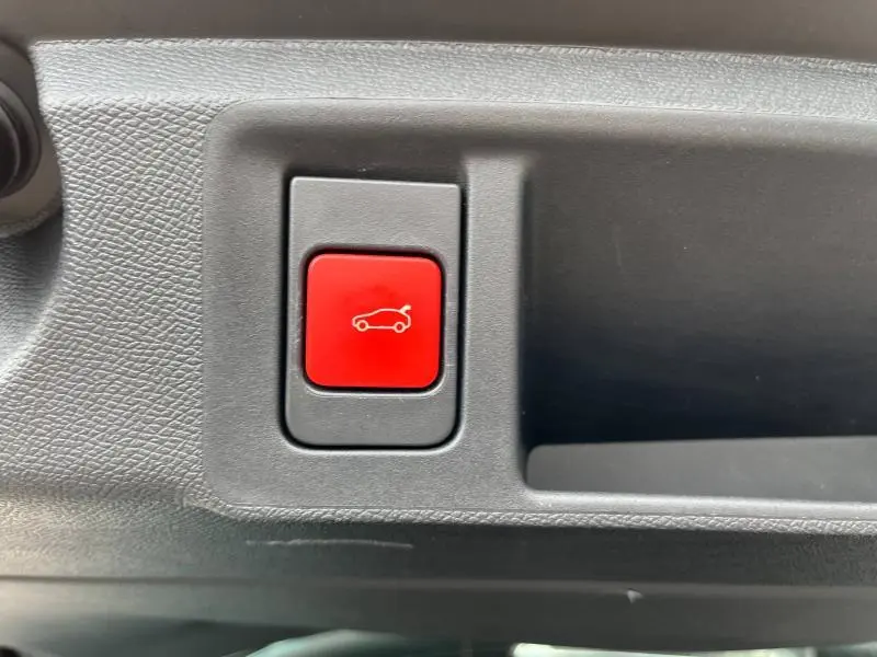 Bouton rouge d'ouverture électrique du coffre sur la garniture intérieure noire d'une Peugeot 308 SW 2023 Bleu Avatar