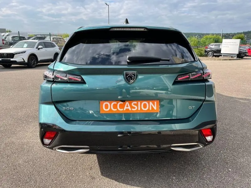 Vue arrière d'une Peugeot 308 SW GT bleu Avatar avec feux LED et double sortie d'échappement chromée sur parking.