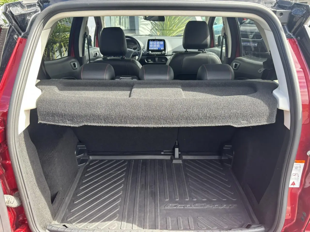 Coffre ouvert d'un Ford EcoSport rouge 2019, vue arrière montrant l'intérieur et l'écran tactile du tableau de bord.