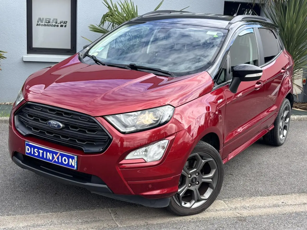 Ford EcoSport rouge métallisé en vue 3/4 avant droit avec jantes alliage et toit noir brillant.