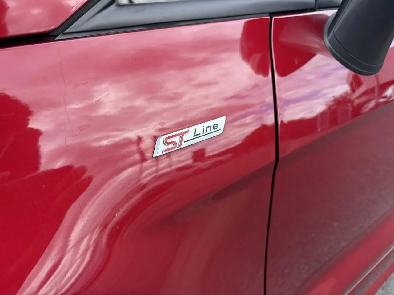Gros plan sur l'écusson ST-Line côté gauche d'un Ford EcoSport rouge métallisé 2019.