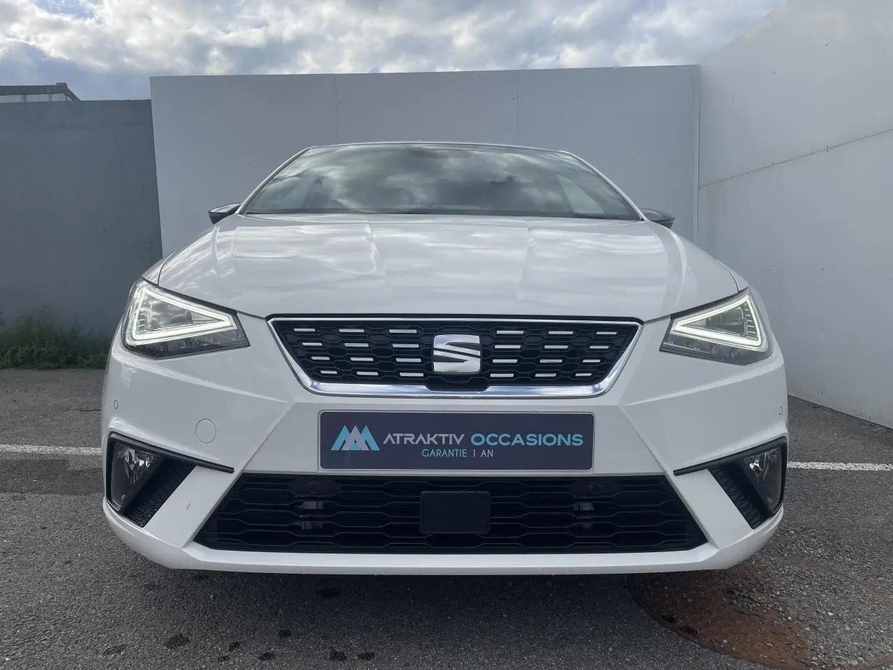 Vue frontale d'une SEAT IBIZA blanche 2025 avec feux LED triangulaires et calandre noire distinctive.