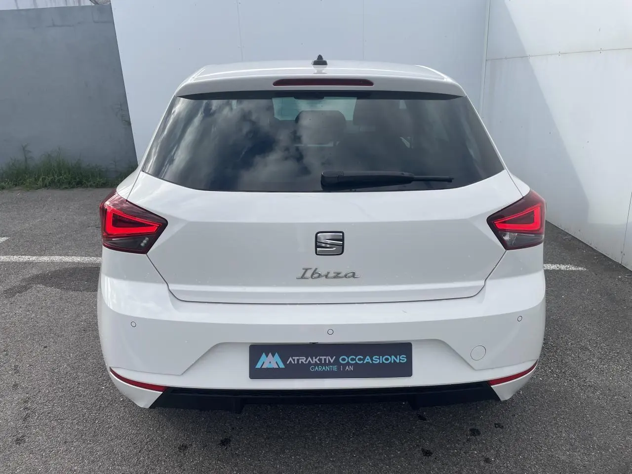 Vue arrière d'une SEAT Ibiza blanche avec feux arrière LED en forme de triangle et lunette arrière teintée.