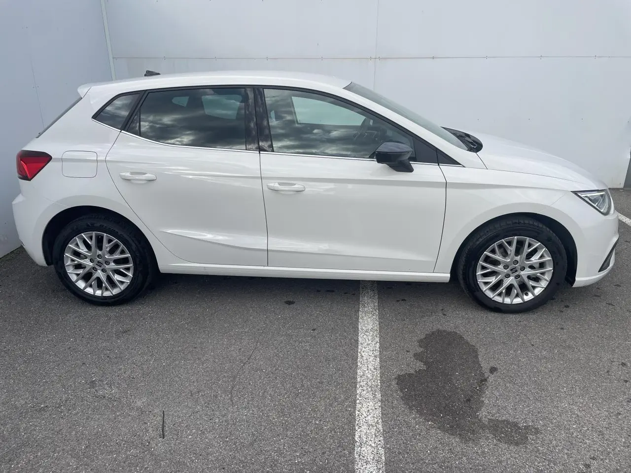 Profil côté gauche d'une SEAT IBIZA blanche 2025 avec jantes alliage et vitres teintées arrière sur parking.