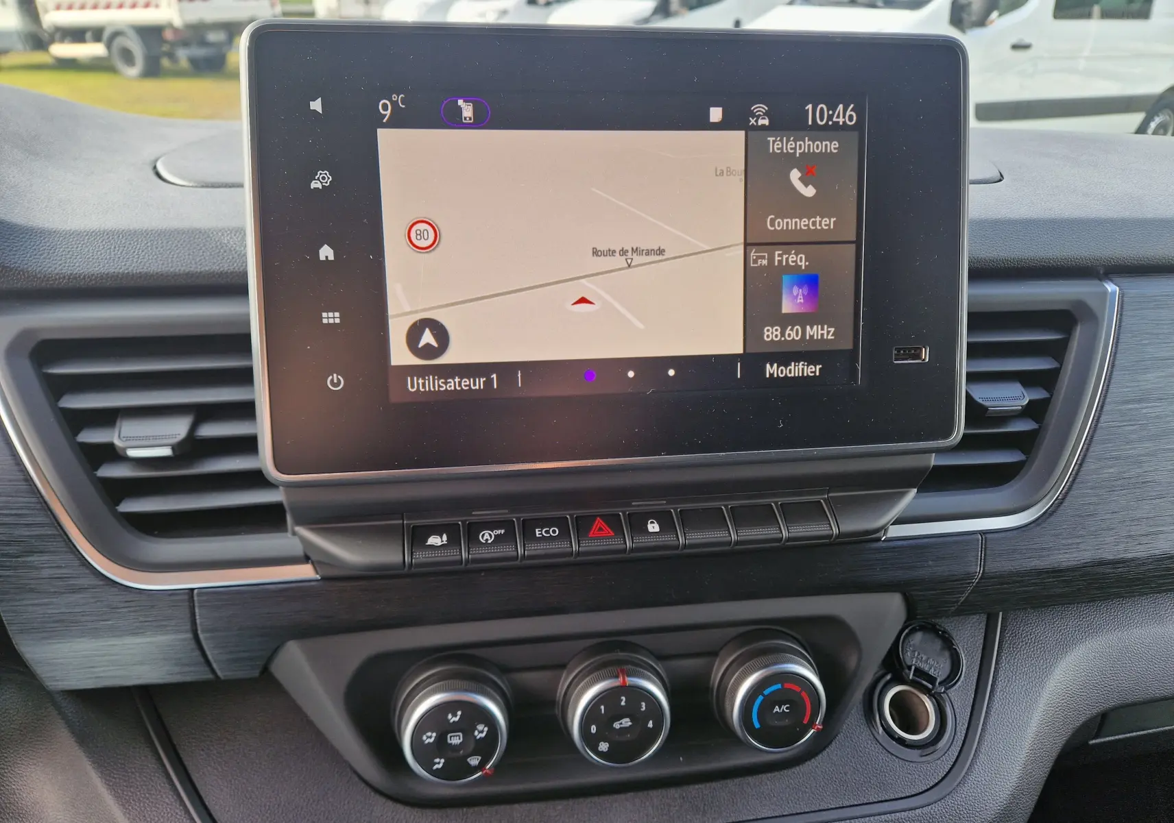Écran tactile central du Nissan Primastar 2025 blanc, vue intérieure sur la console avec navigation et commandes climatiques.