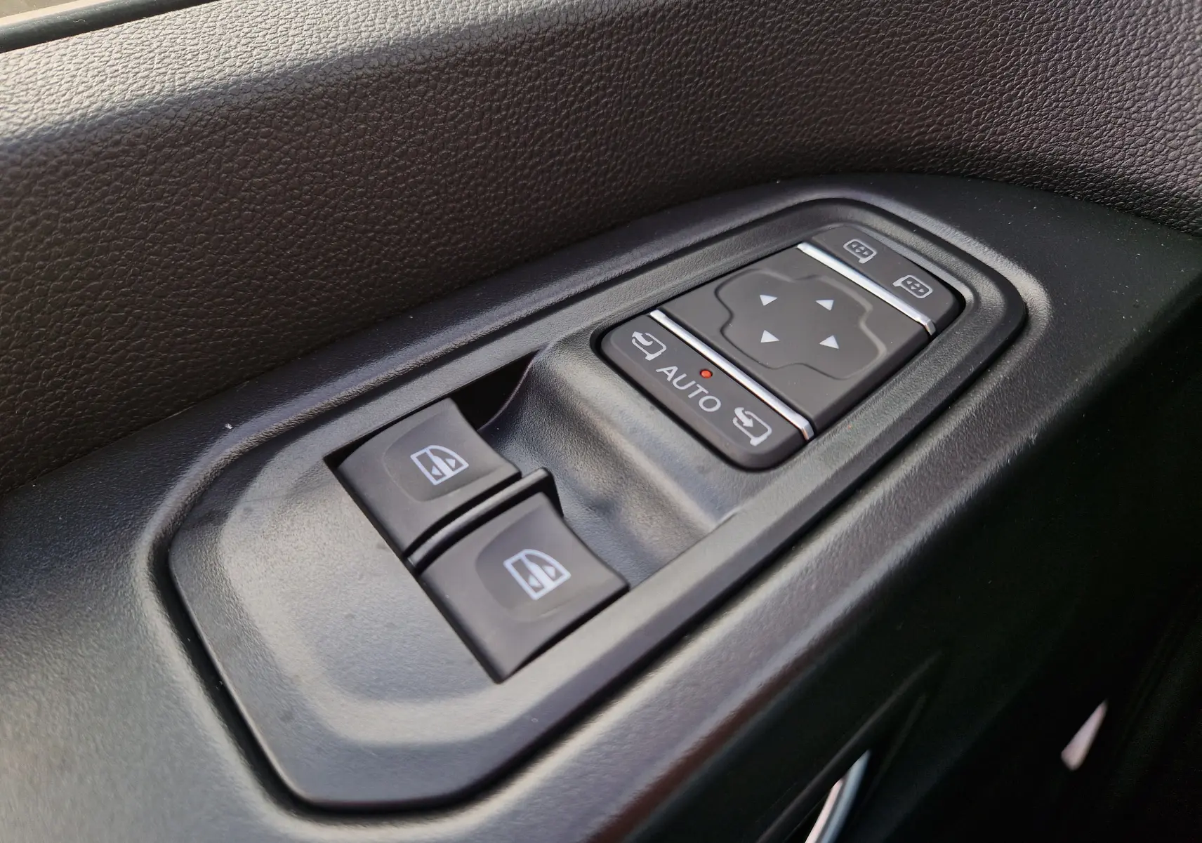 Gros plan sur les commandes de lève-vitres et réglage des rétroviseurs côté conducteur du Nissan Primastar blanc 2025.