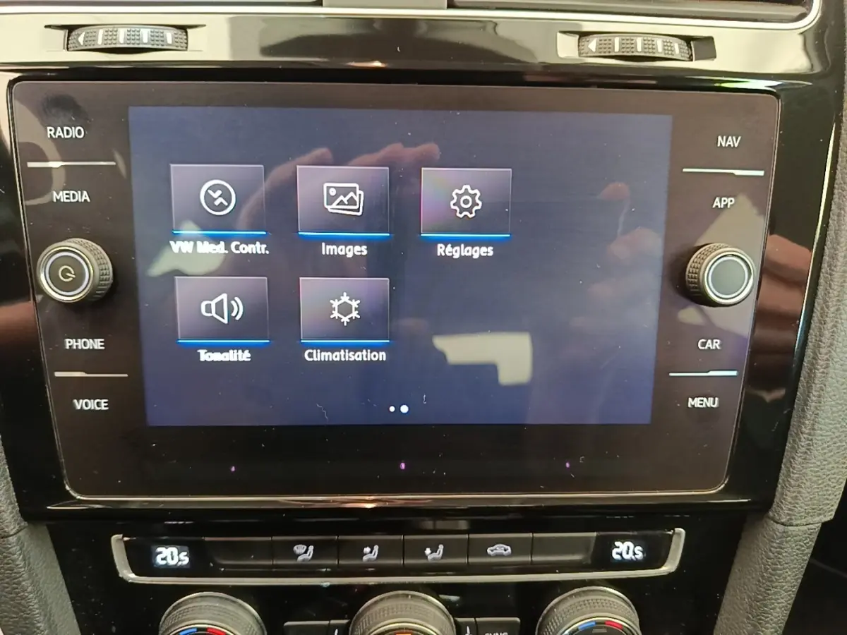 Gros plan sur l'écran tactile central et les commandes de climatisation d'une Volkswagen Golf bleue de 2020.