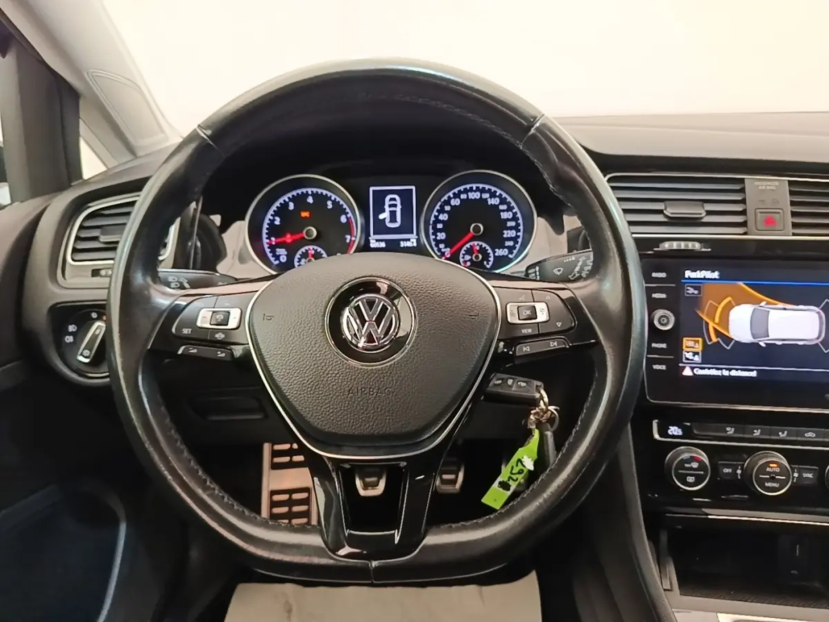 Vue intérieure centrée sur le volant cuir multifonctions d'une Volkswagen Golf 2020 avec tableau de bord et écran tactile.