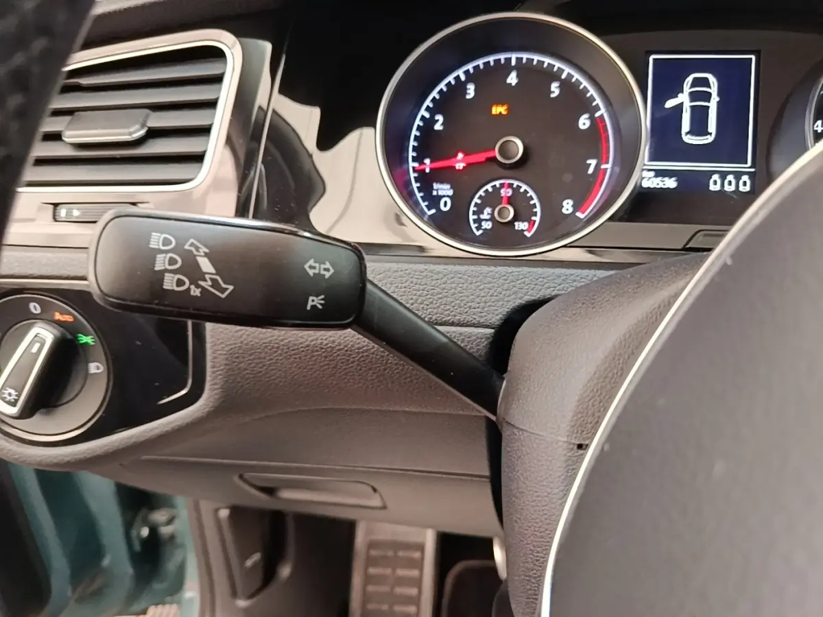 Gros plan sur le tableau de bord et commodo gauche de la Volkswagen Golf bleue, avec compte-tours et affichage digital.