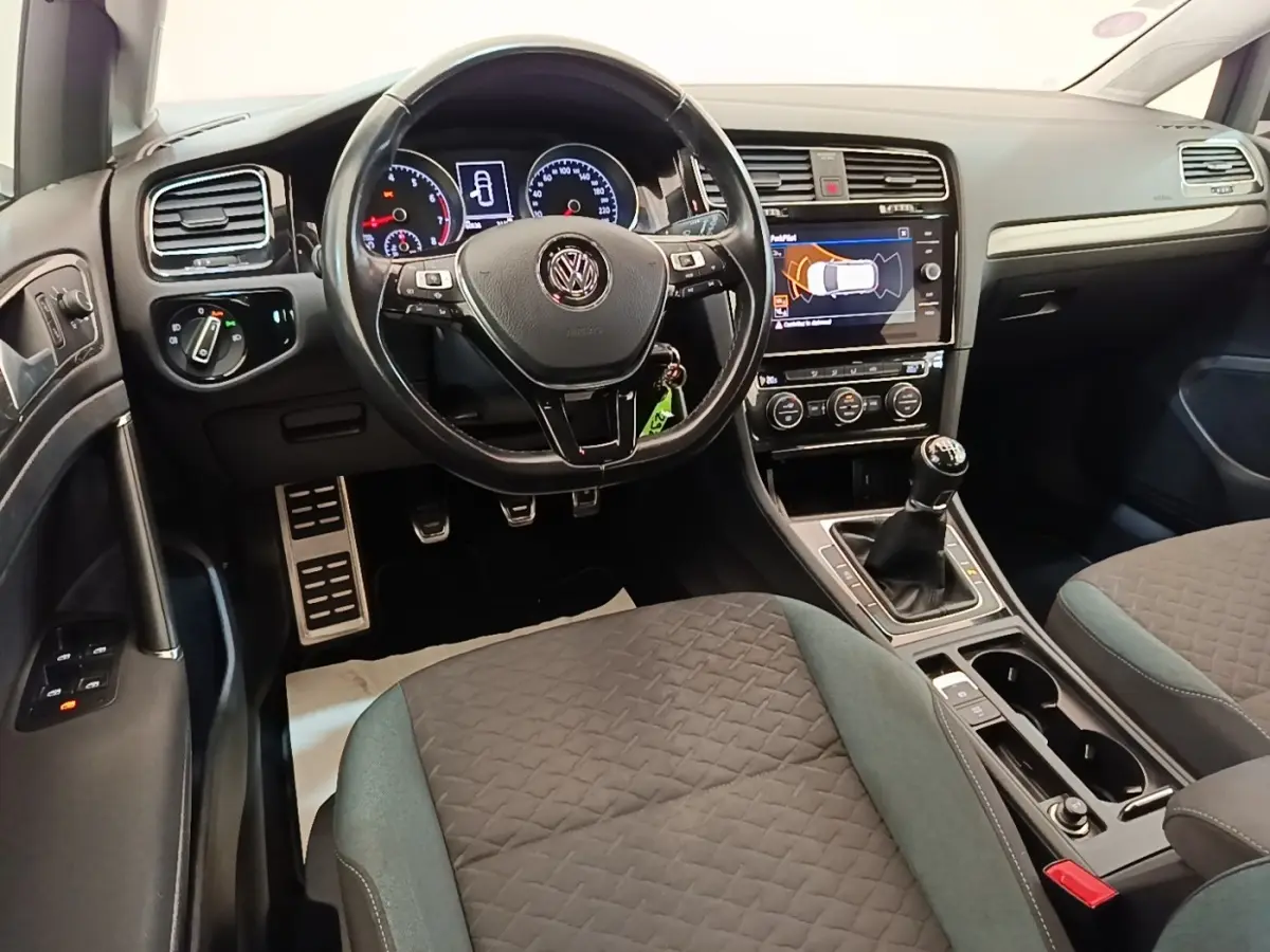 Vue intérieure avant de la Volkswagen Golf 1.0 TSI bleue, volant cuir multifonctions et boîte manuelle visible.