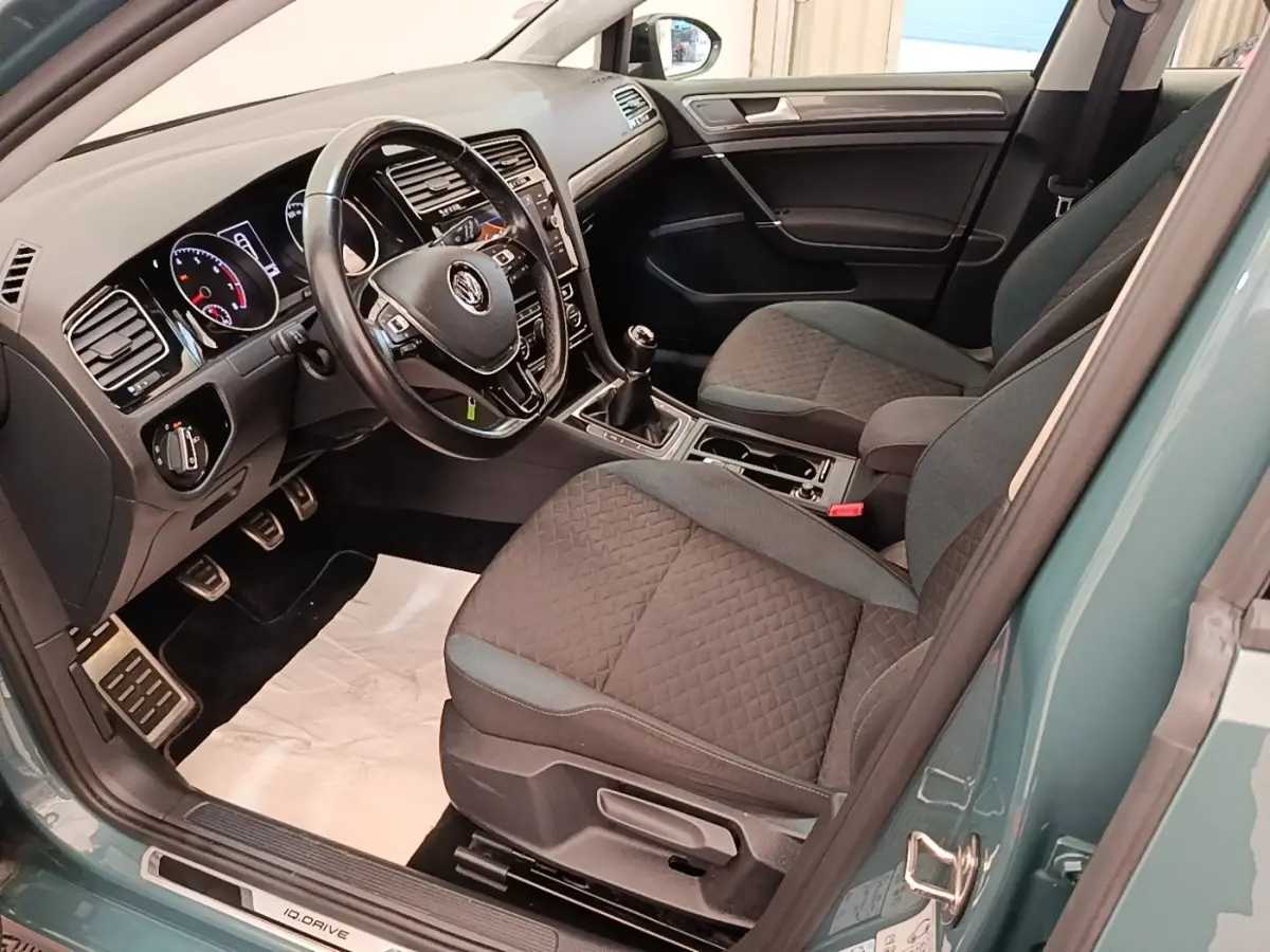 Vue intérieure côté conducteur d'une Volkswagen Golf bleu 2020, volant cuir multifonctions et sièges tissu gris.