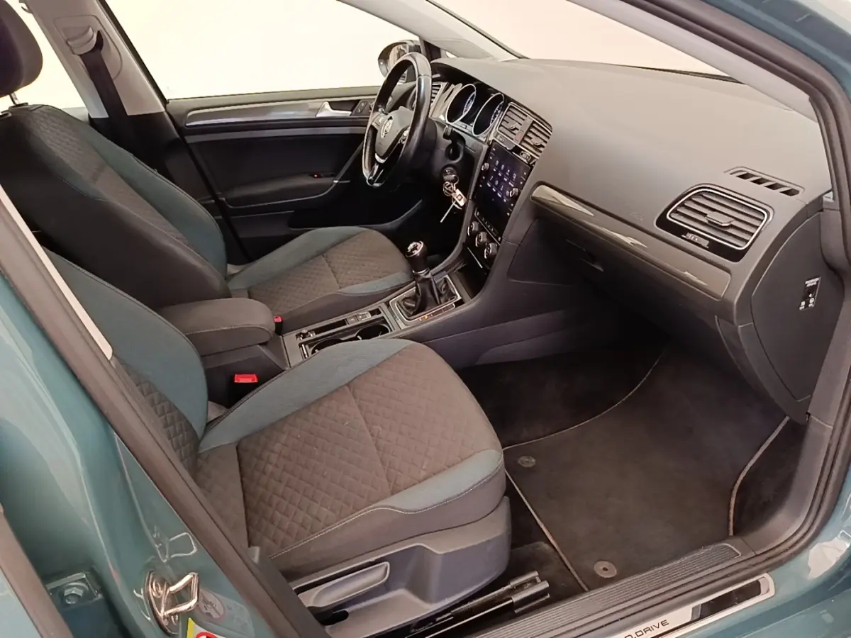Vue intérieure côté conducteur de la Volkswagen Golf 1.0 TSI bleu, avec volant cuir multifonctions et tableau de bord tactile.