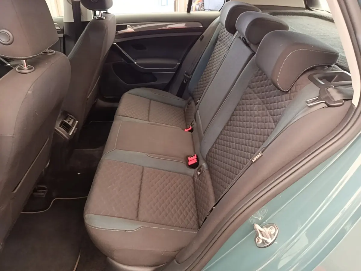 Vue intérieure côté droit sur la banquette arrière gris foncé à motifs losanges d’une Volkswagen Golf bleue.