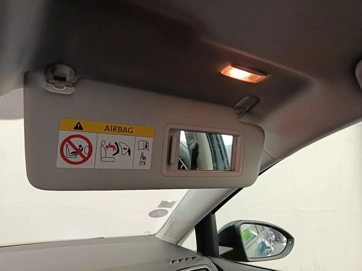 Vue intérieure du pare-soleil côté conducteur avec miroir intégré et avertissement airbag sur une Volkswagen Golf bleue.