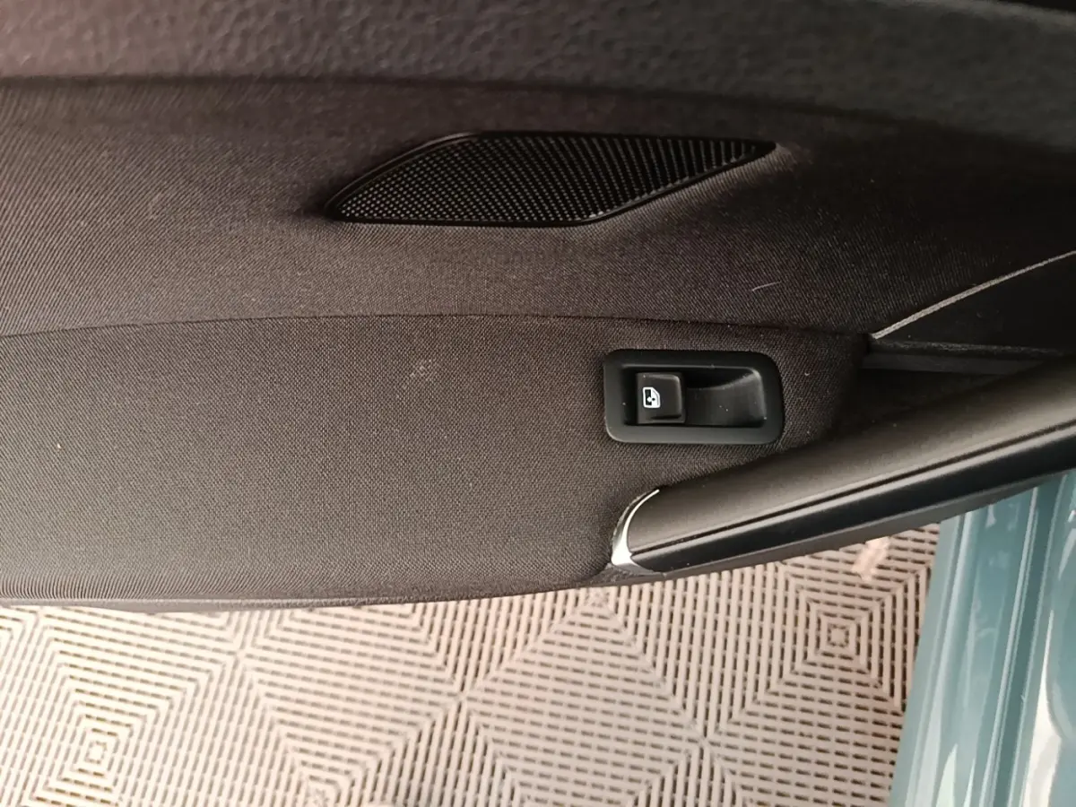 Détail de la poignée intérieure de porte arrière droite d’une Volkswagen Golf bleue, tissu noir et bouton de verrouillage.