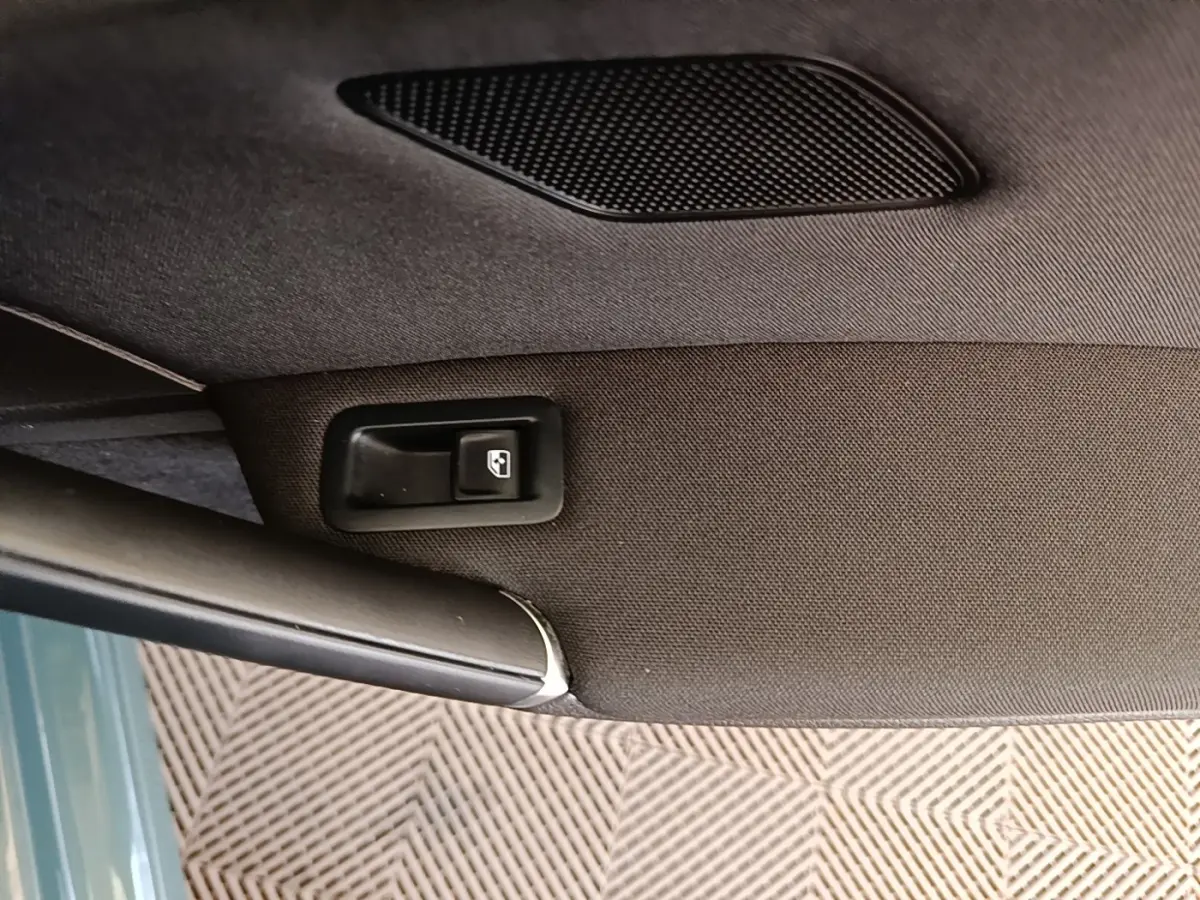 Détail de la commande de lève-vitre sur la porte intérieure d’une Volkswagen Golf bleue.