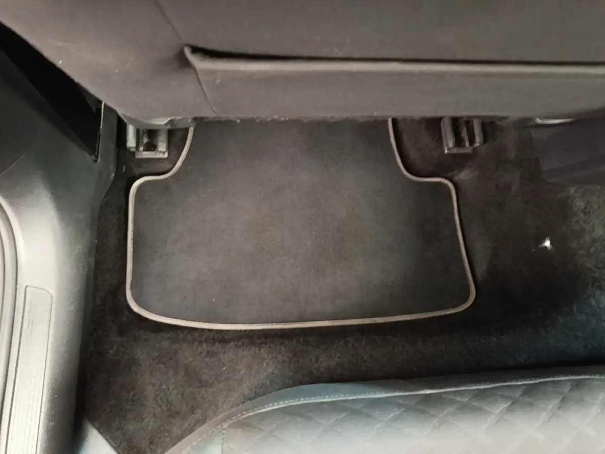 Vue du tapis de sol noir côté passager arrière d'une Volkswagen Golf bleue 2020, intérieur sobre et propre.
