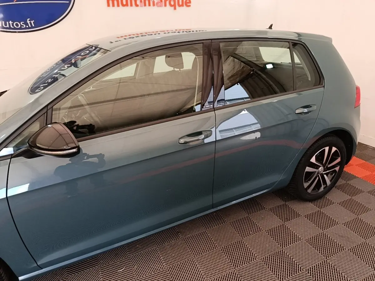 Vue latérale gauche d'une Volkswagen Golf bleu métallisé avec jantes alliage et rétroviseur noir.