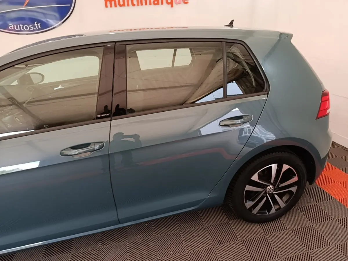 Vue côté droit arrière d'une Volkswagen Golf bleu métallisé avec jantes alliage et vitres teintées.