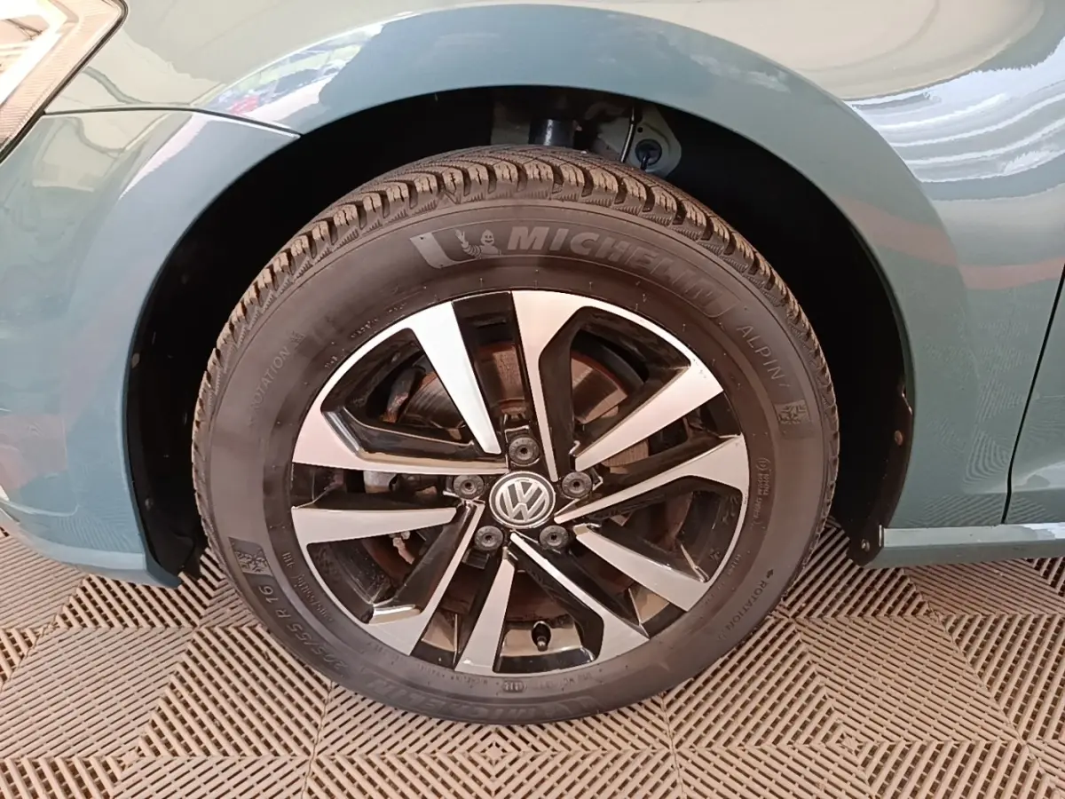 Gros plan sur la roue avant droite d’une Volkswagen Golf bleu 2020 avec jante alliage bicolore et pneu Michelin.