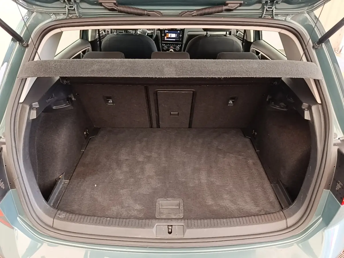 Vue arrière du coffre ouvert d’une Volkswagen Golf bleu 2020, intérieur noir avec tablette de séparation visible.