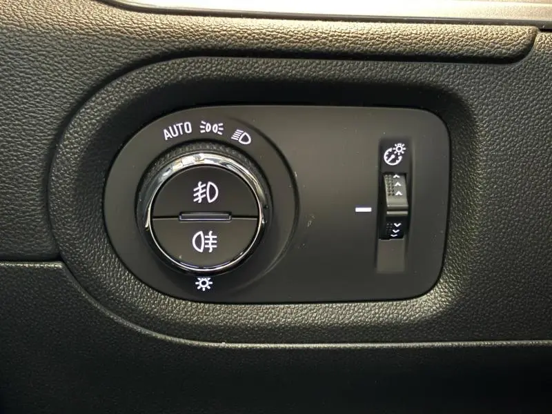 Gros plan sur la commande des phares et réglage de luminosité dans l'habitacle noir de l'Opel Grandland 2022.